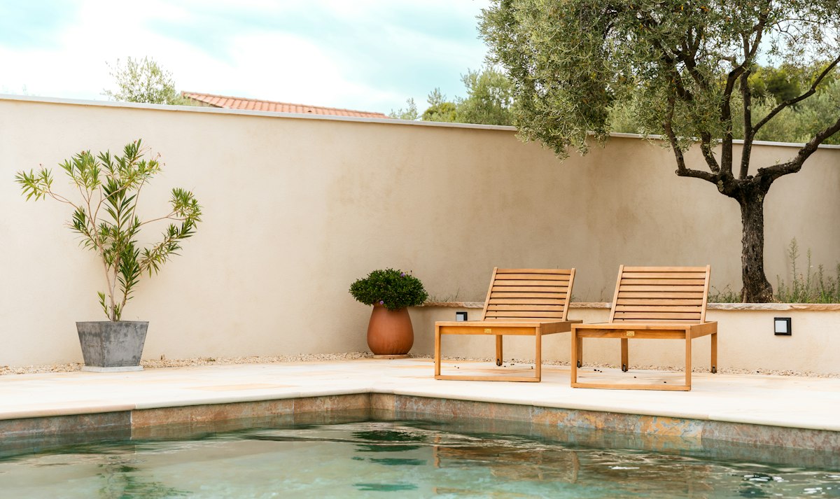 Sunny pool terrace with two wooden loungers at a home in the south of France